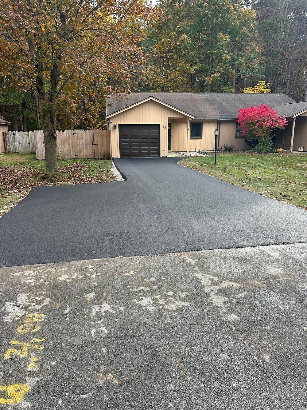 Asphalt paving in progress; a person operates a compactor on fresh blacktop.