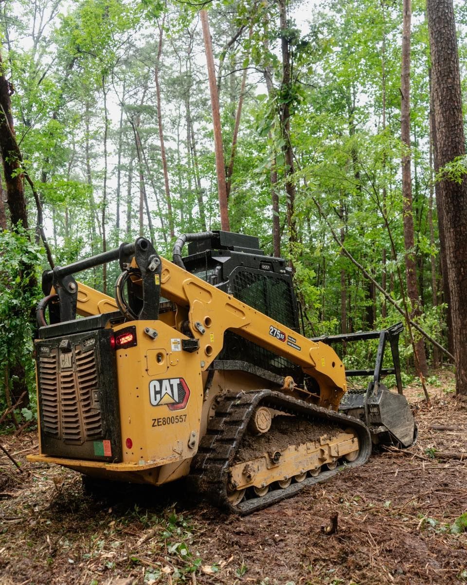 Yellow Caterpillar skid steer in a wooded area.