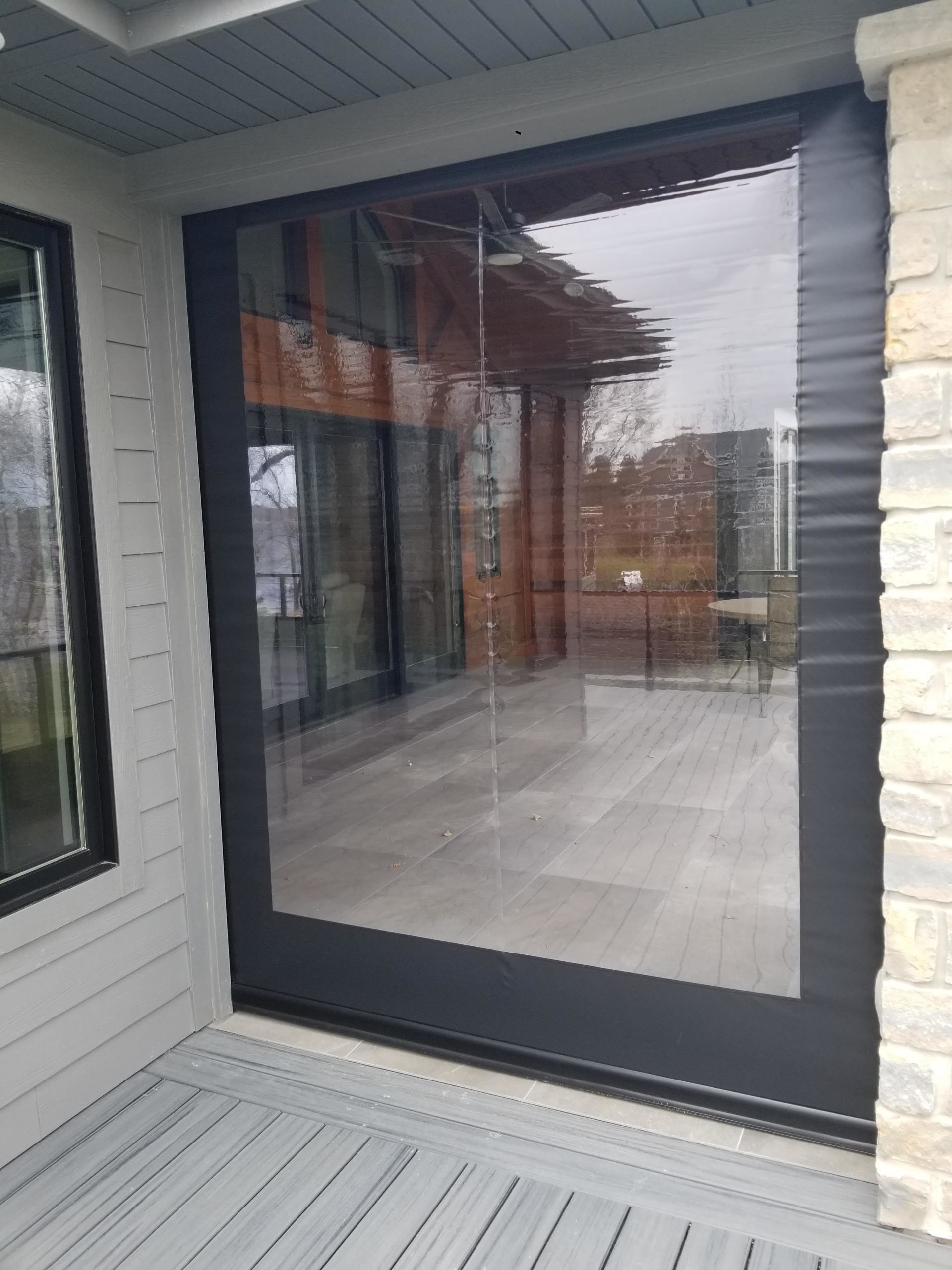 Clear outdoor screen installed on a porch with a black frame. The screen provides visibility to the patio.