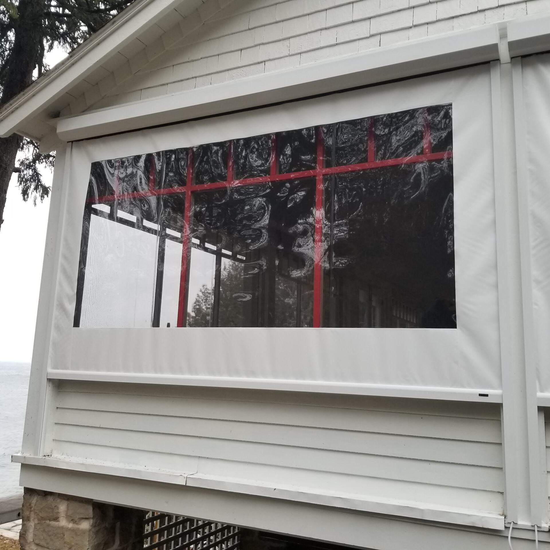 White building with a large clear vinyl window covering. Red interior framing is visible through the window.