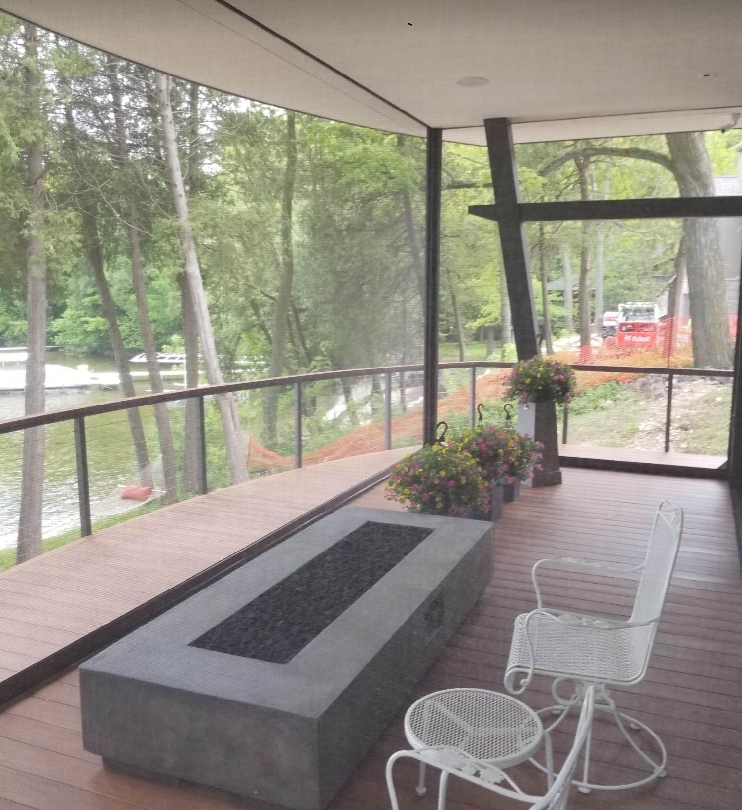 A screened porch with a river view, a modern fireplace, and white patio furniture.