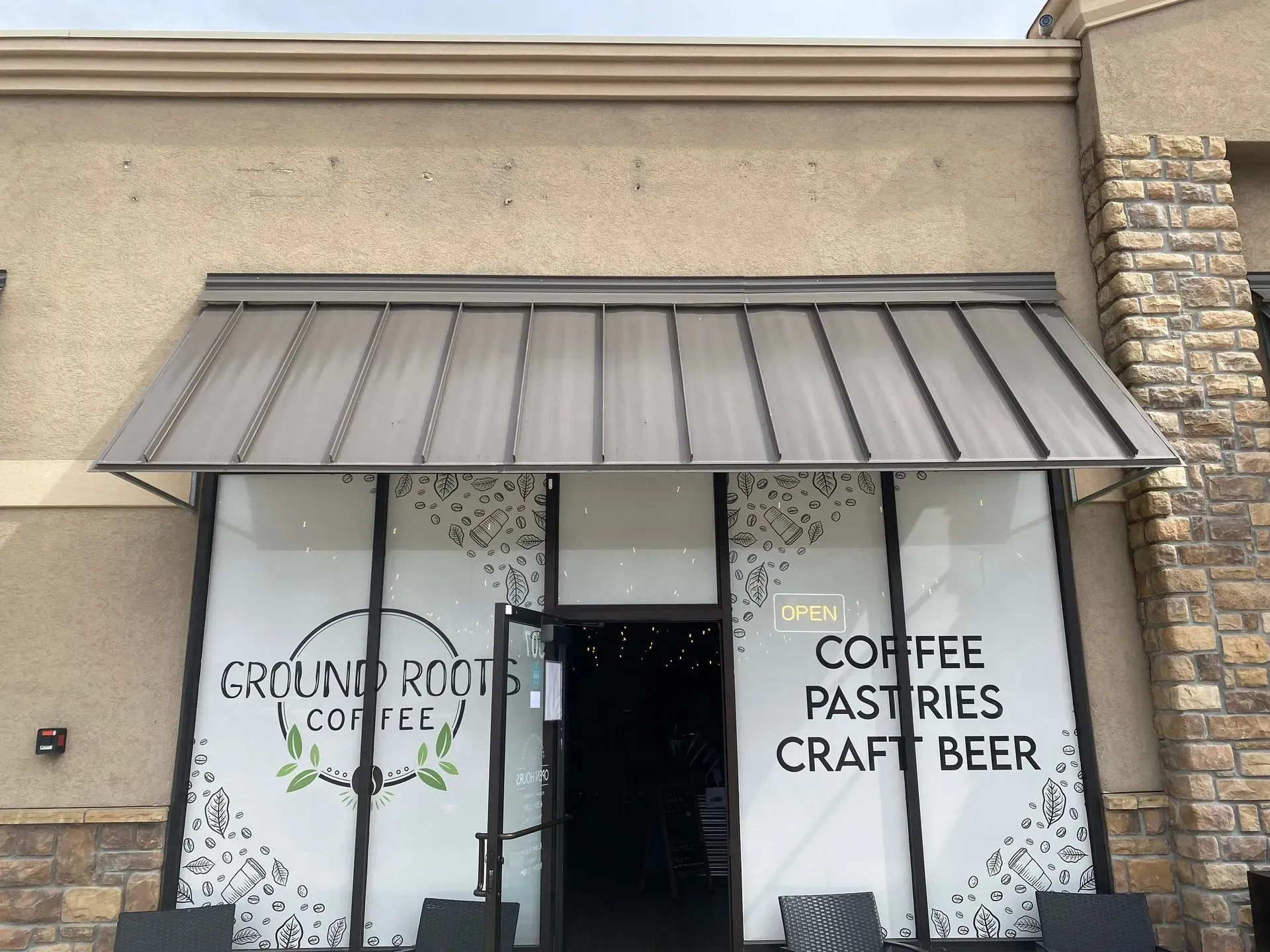 Ground Roots Coffee shop exterior with awning and open door; offers coffee, pastries, and craft beer.
