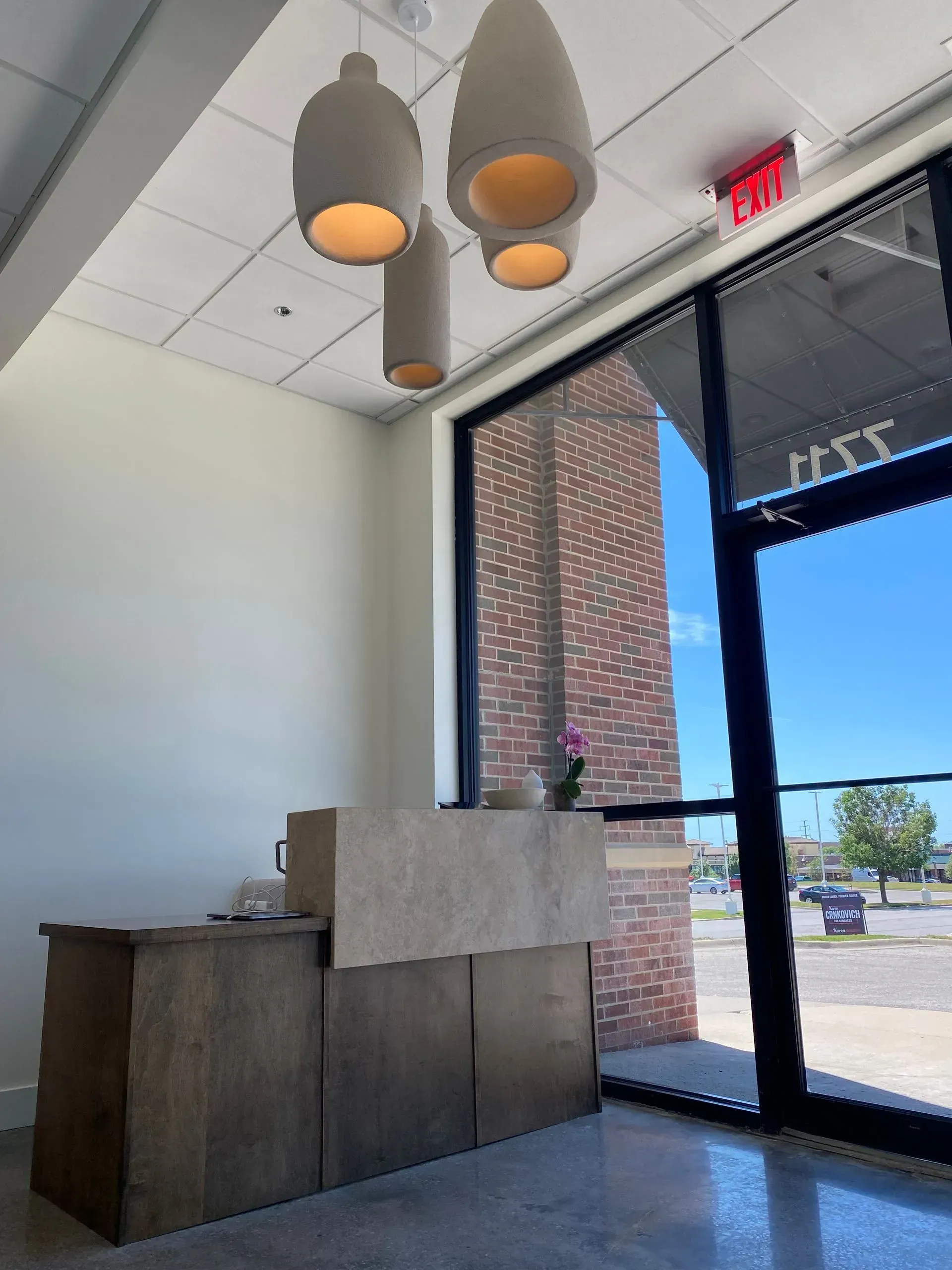 Reception desk under pendant lights by a window, with an exterior view.