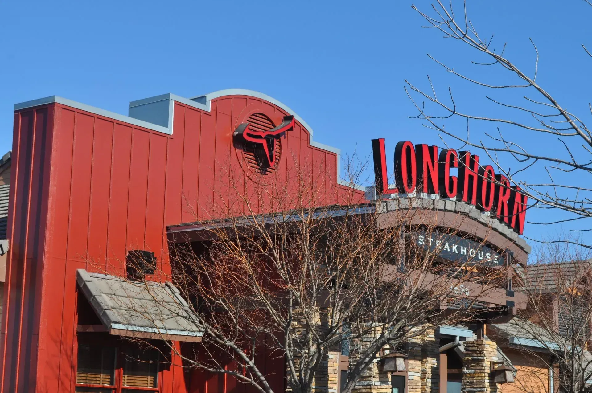 LongHorn Steakhouse building with red exterior and signage under a clear, blue sky.