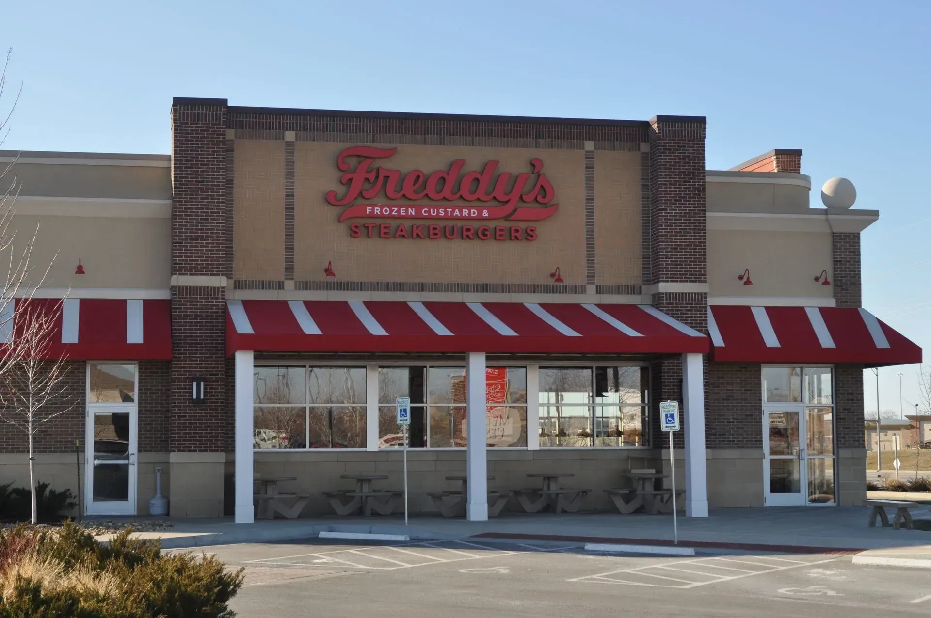 Freddy's Frozen Custard & Steakburgers restaurant exterior with red awning, sign, and brick accents.