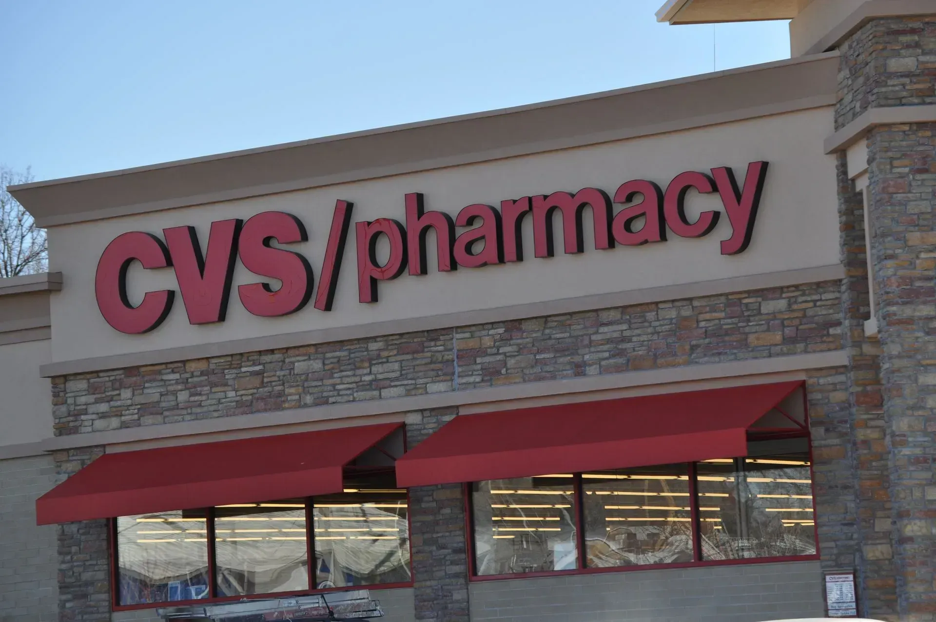 CVS/pharmacy store sign with red lettering on a beige background. Red awnings cover the windows.