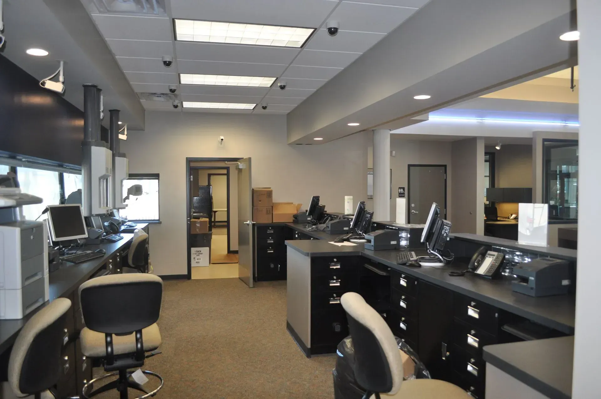 Interior office with desks, chairs, computers, and surveillance cameras.
