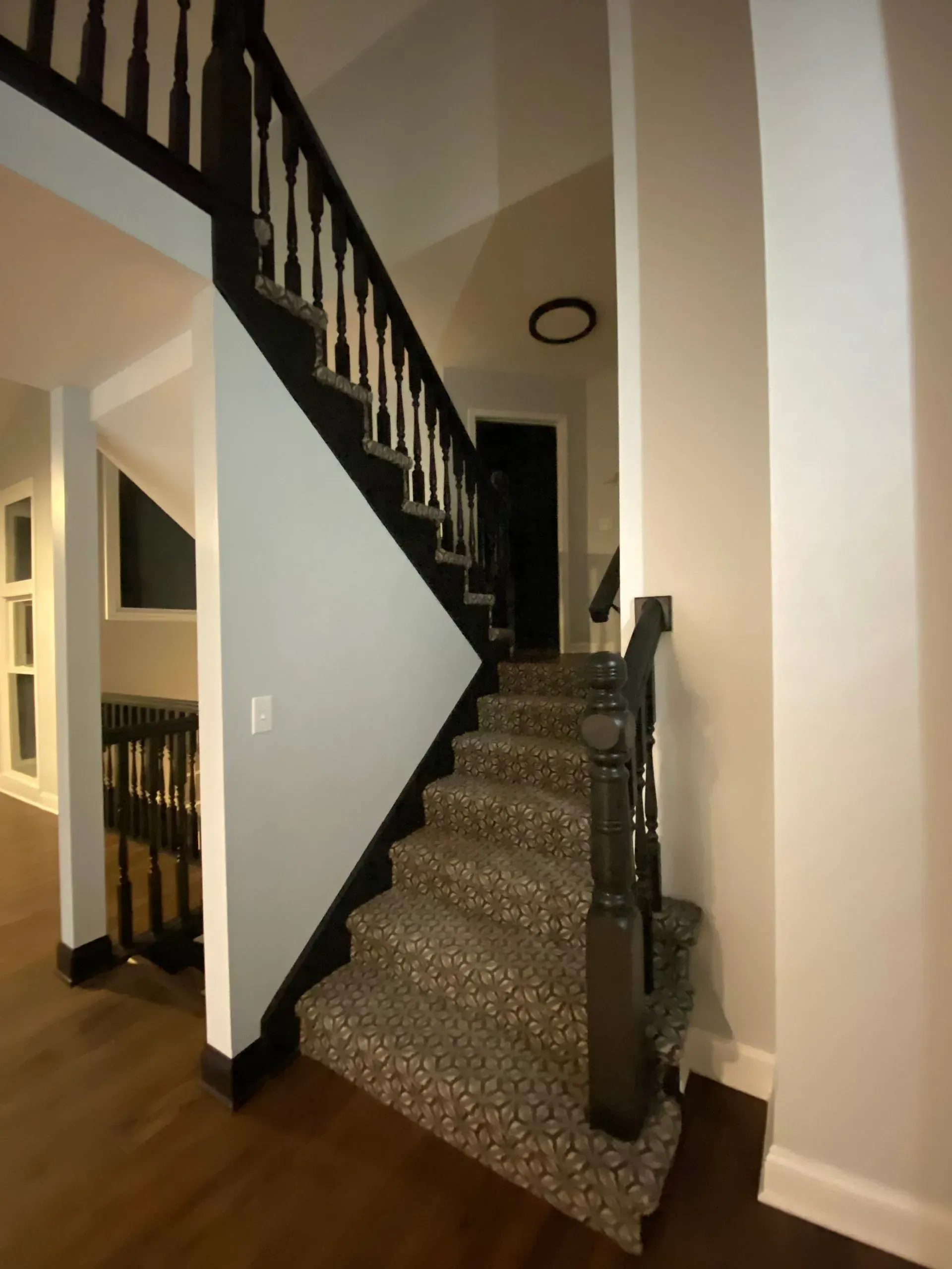 Staircase with black banisters and patterned carpet on the steps; light blue and gray walls.