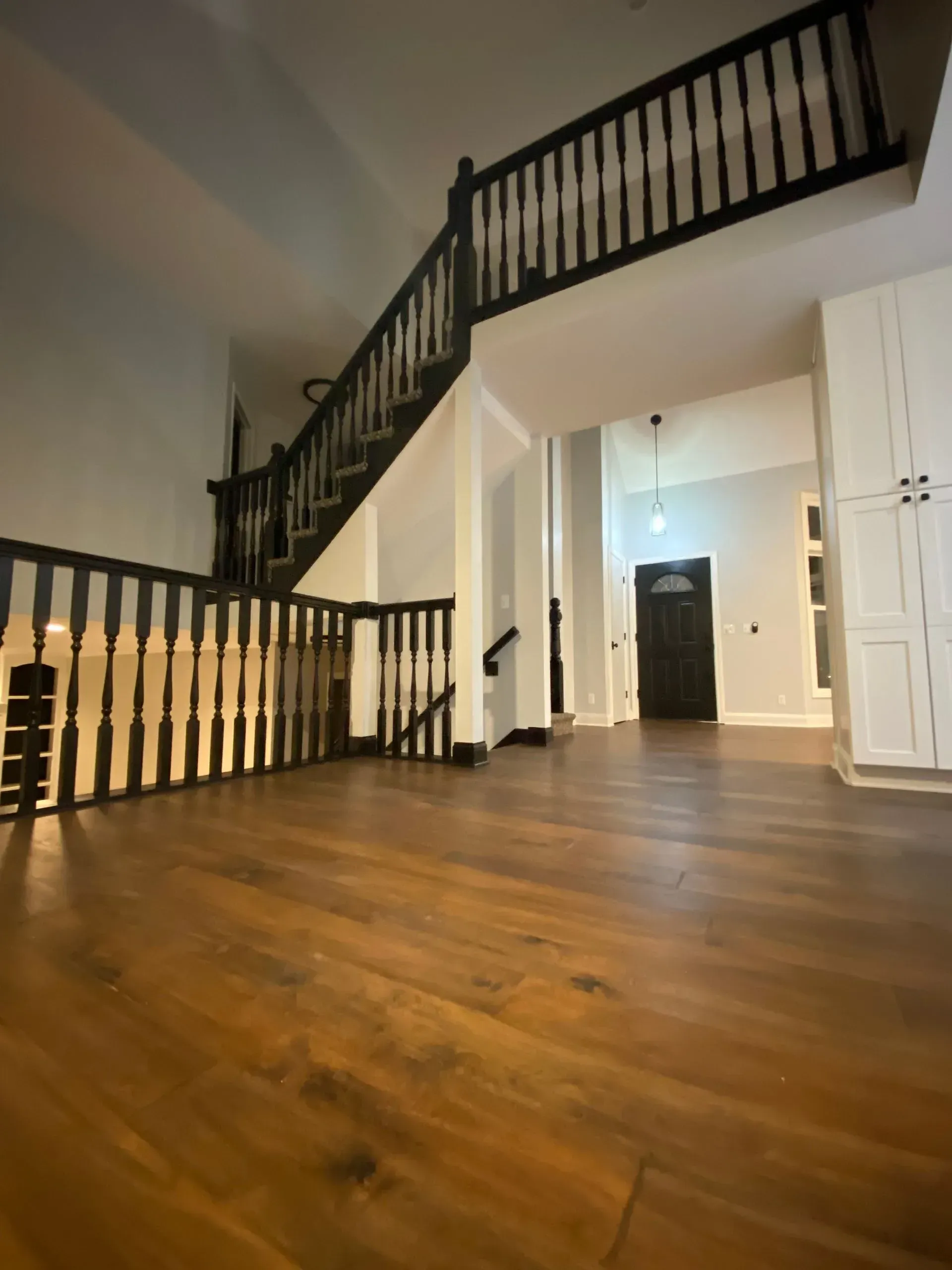 Wooden staircase in a modern home, leading to a second floor. Dark wood floors and railings.