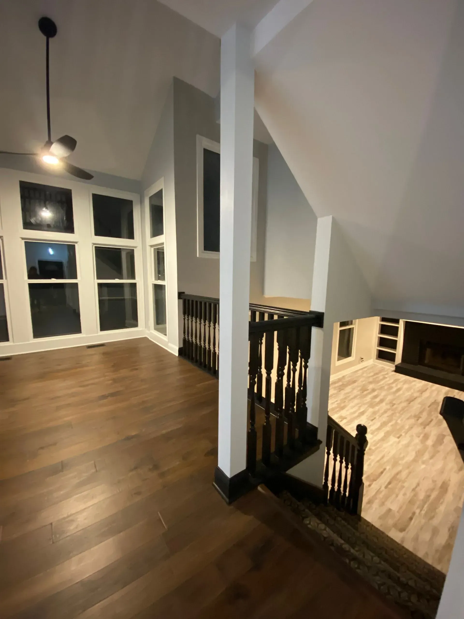Interior of a home with hardwood floors, staircase, windows, and white columns.