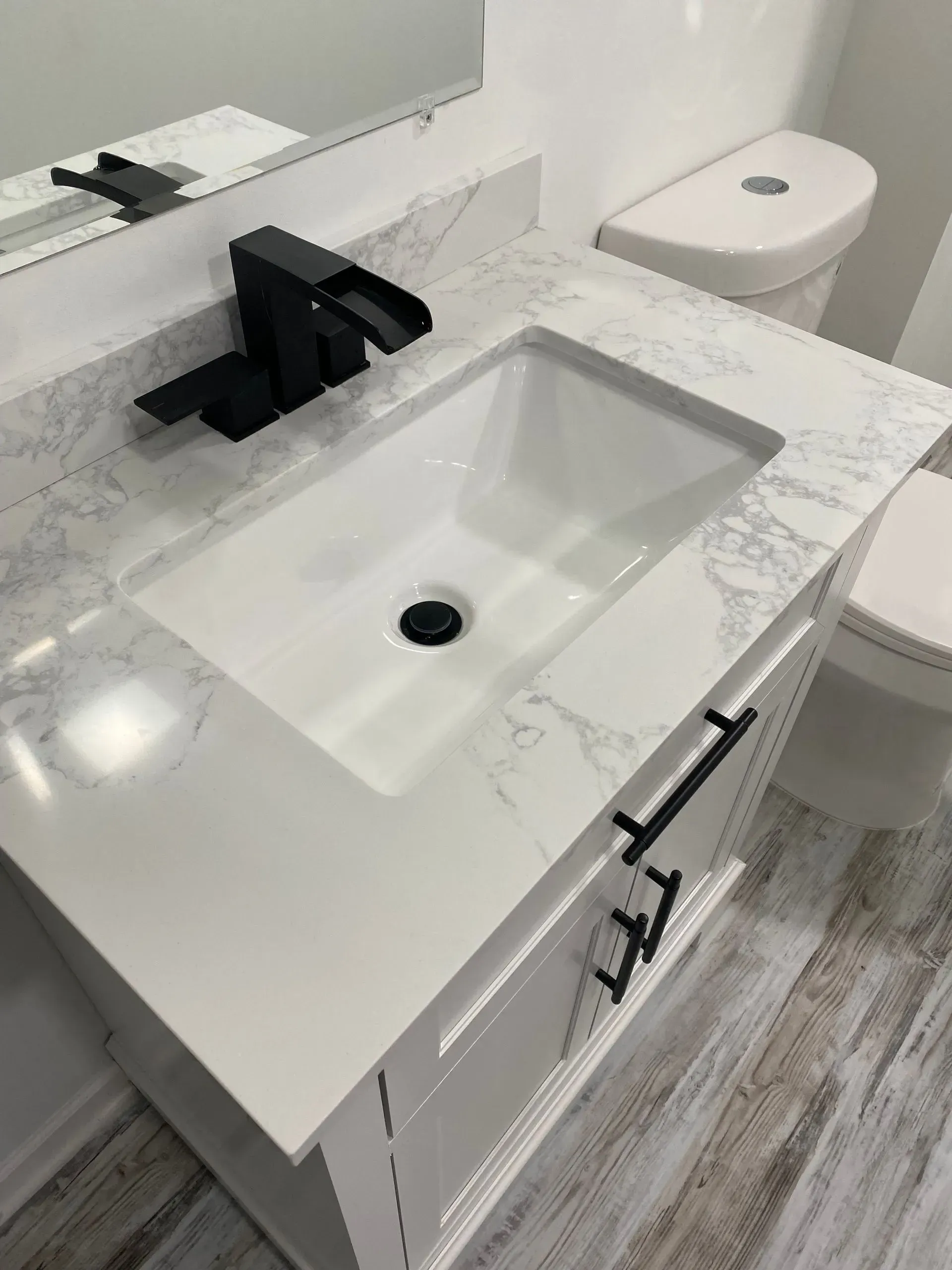 Bathroom vanity with white countertop, black faucet, and white sink.