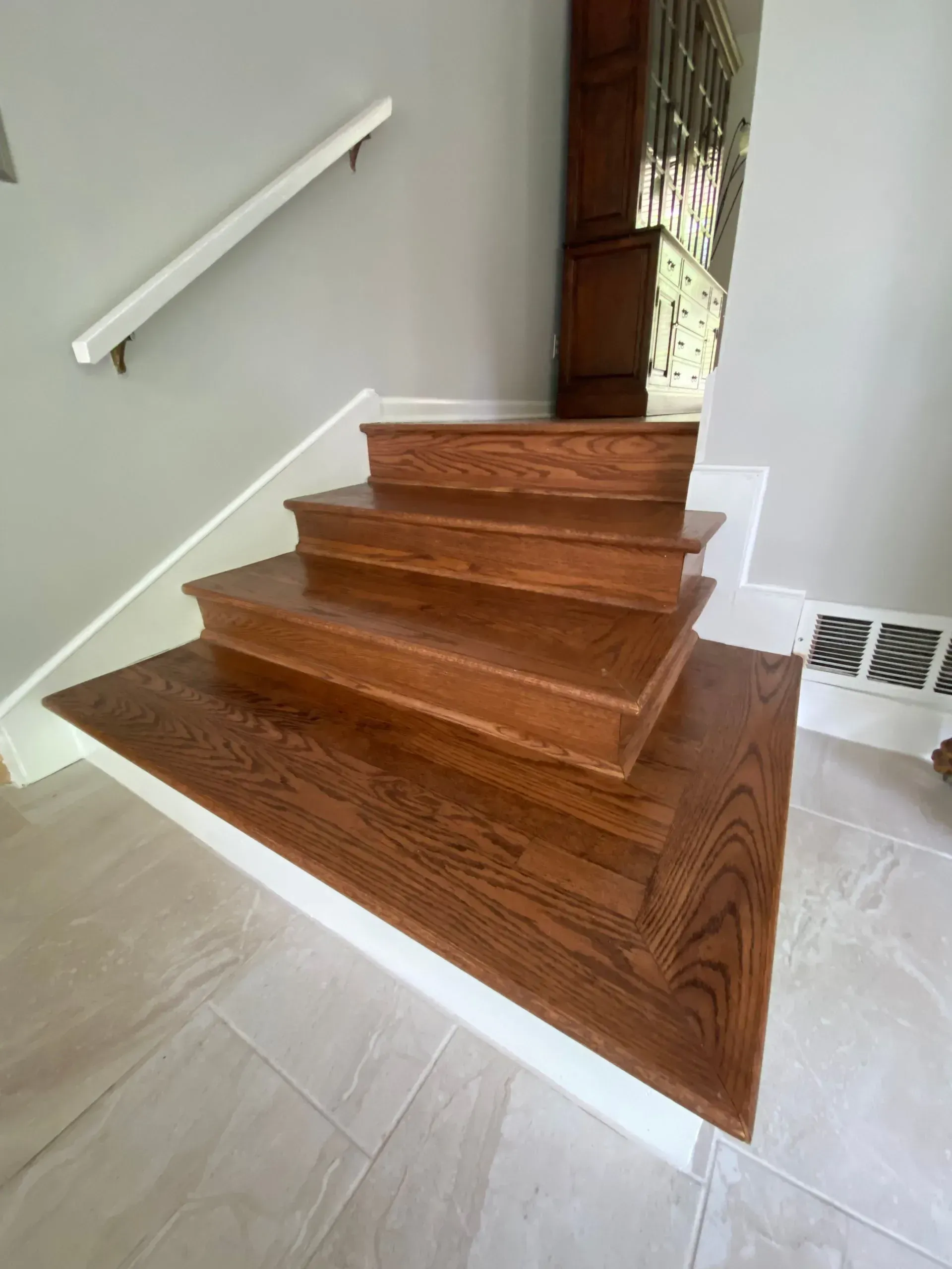 Wooden staircase with stained treads and risers, white trim, and a handrail.