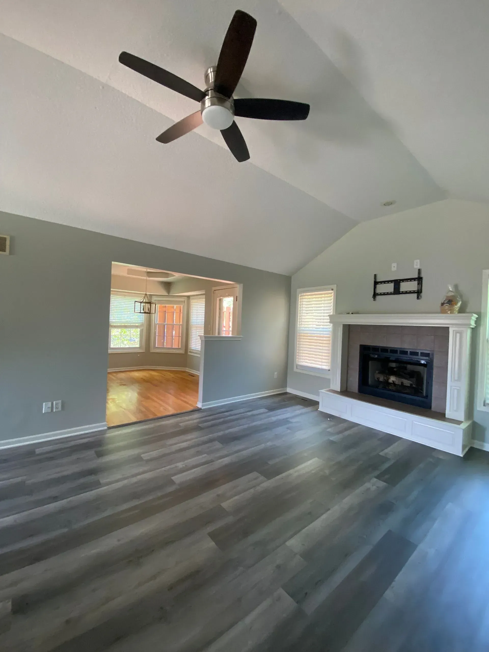 Living room with gray walls, dark wood floor, fireplace, and ceiling fan.