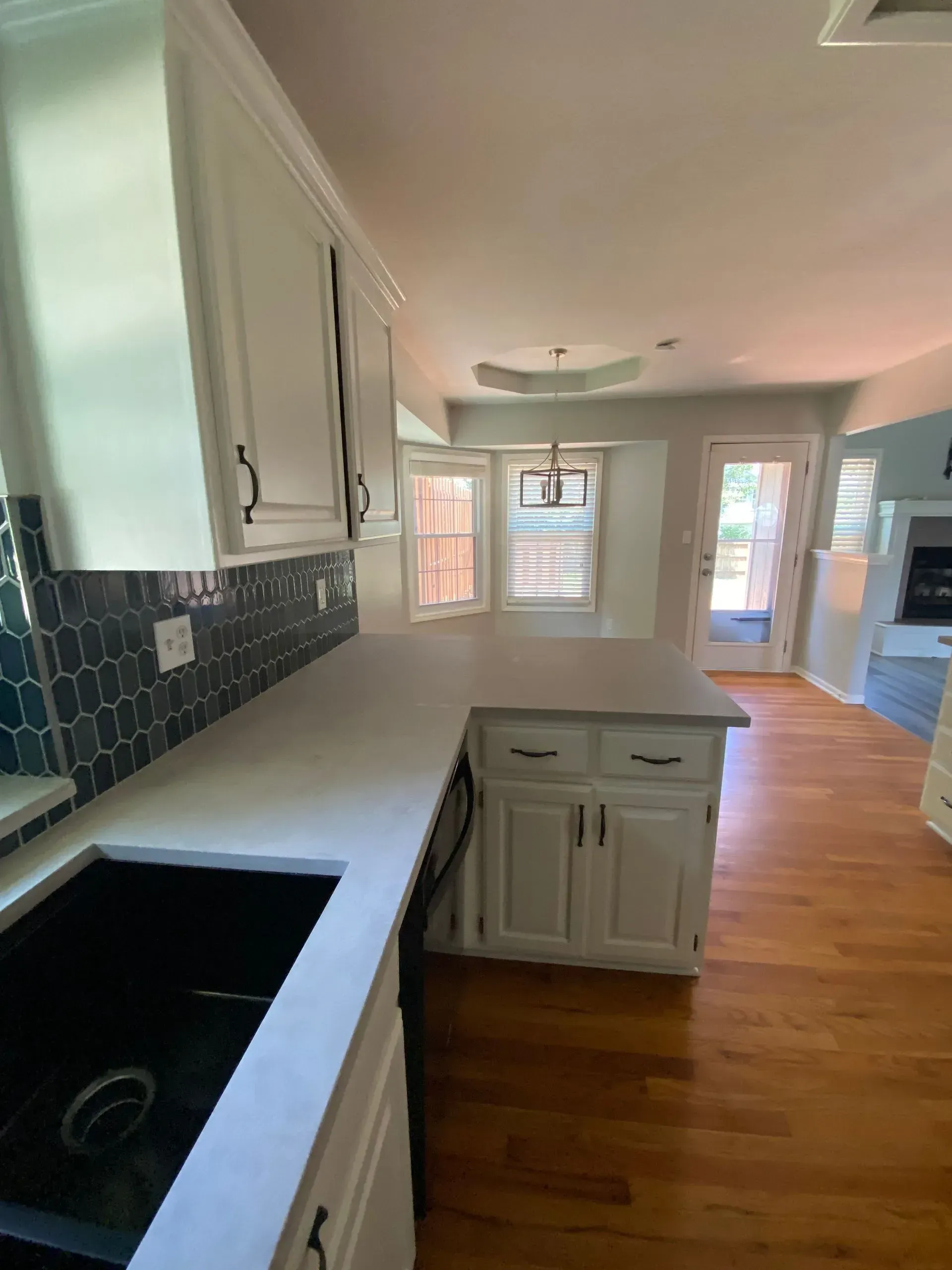 White kitchen with blue tile backsplash, countertops, and wood floors.