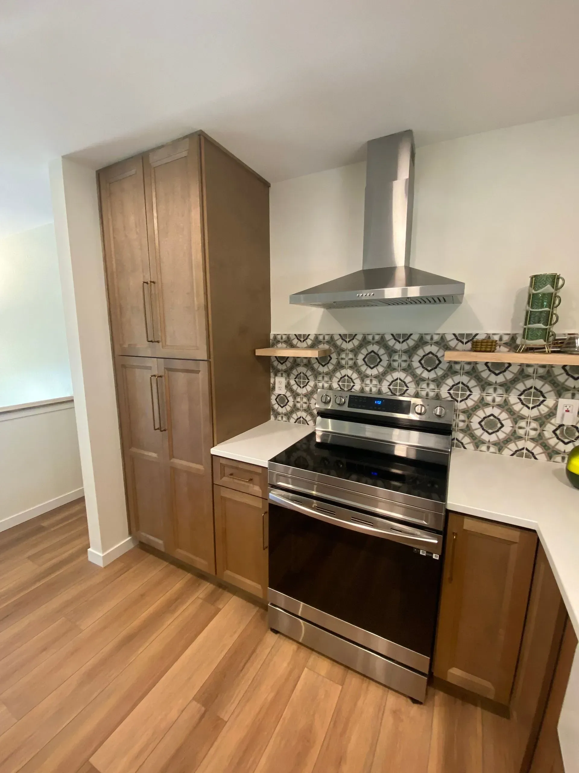 Kitchen with light wood cabinets, stainless steel appliances, and patterned tile backsplash.