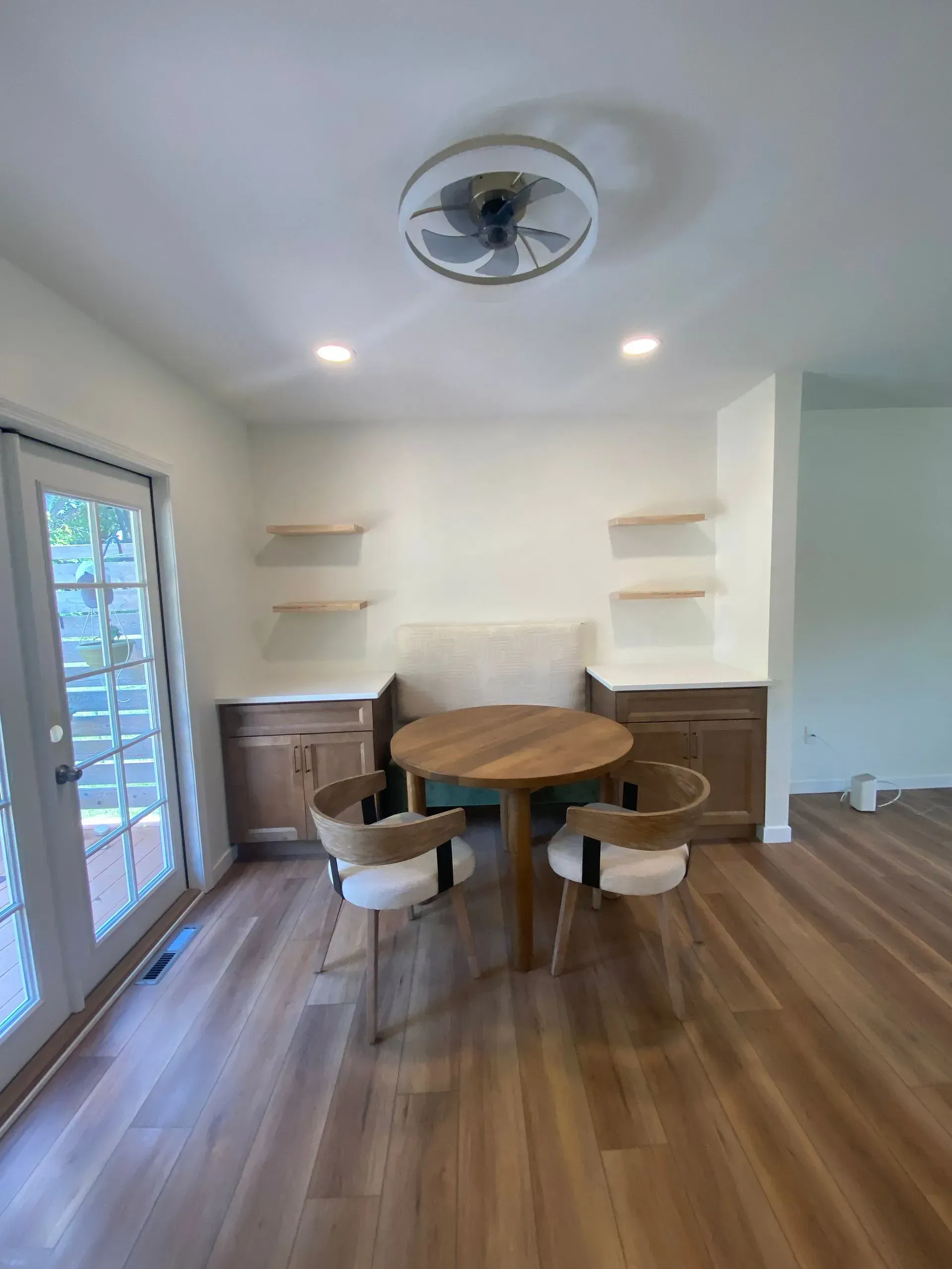 Dining room with round wooden table, two chairs, and built-in cabinetry with shelves.