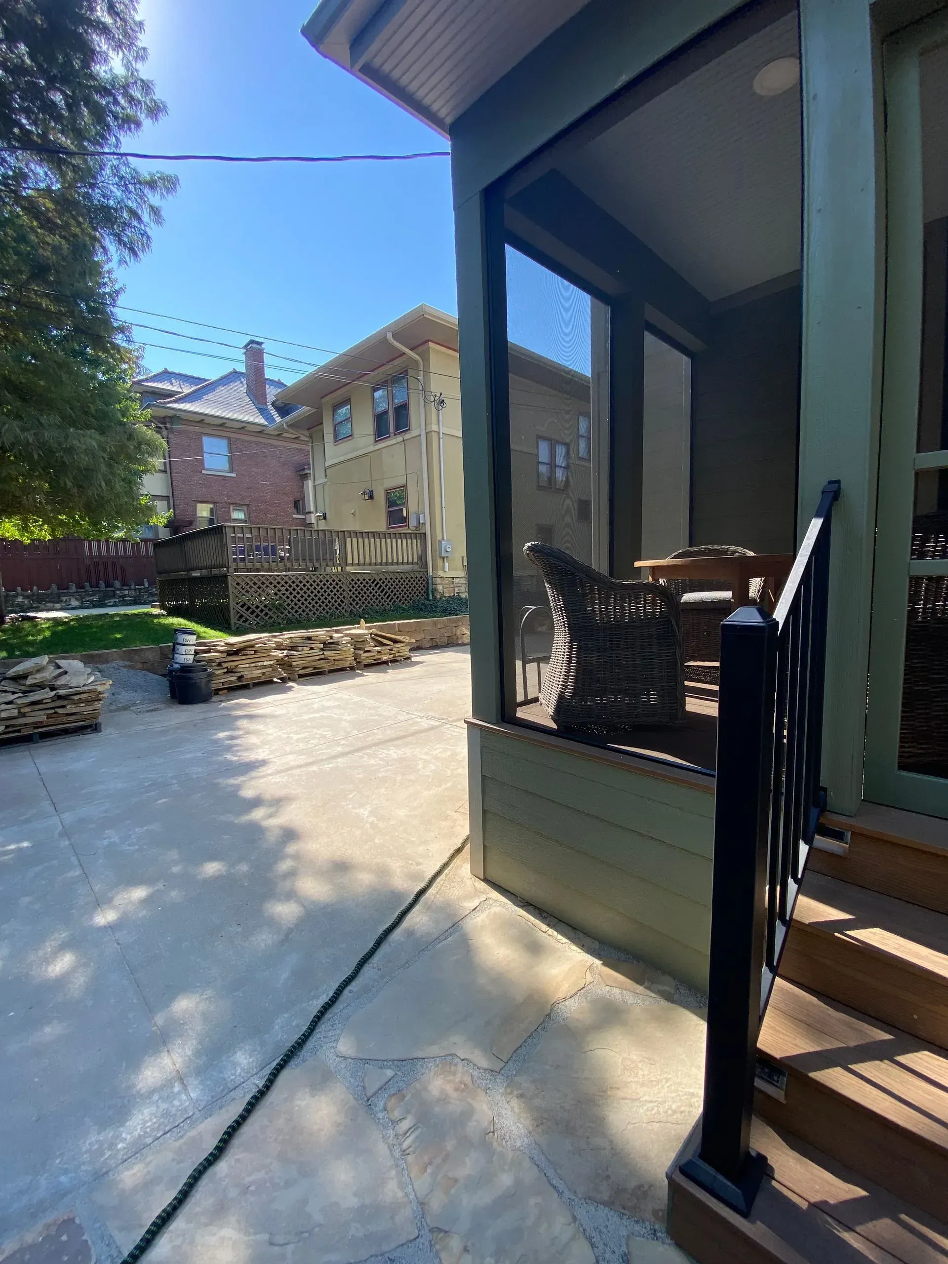 Concrete patio with porch and adjacent building in sunny setting.