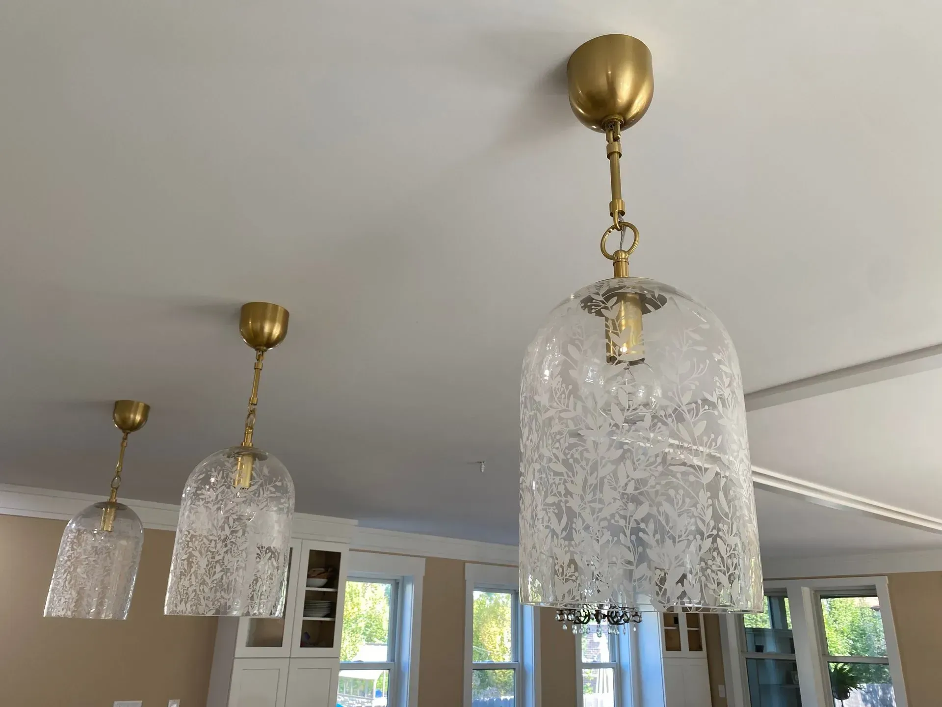 Three glass pendant lights with brass fixtures hanging from a white ceiling.