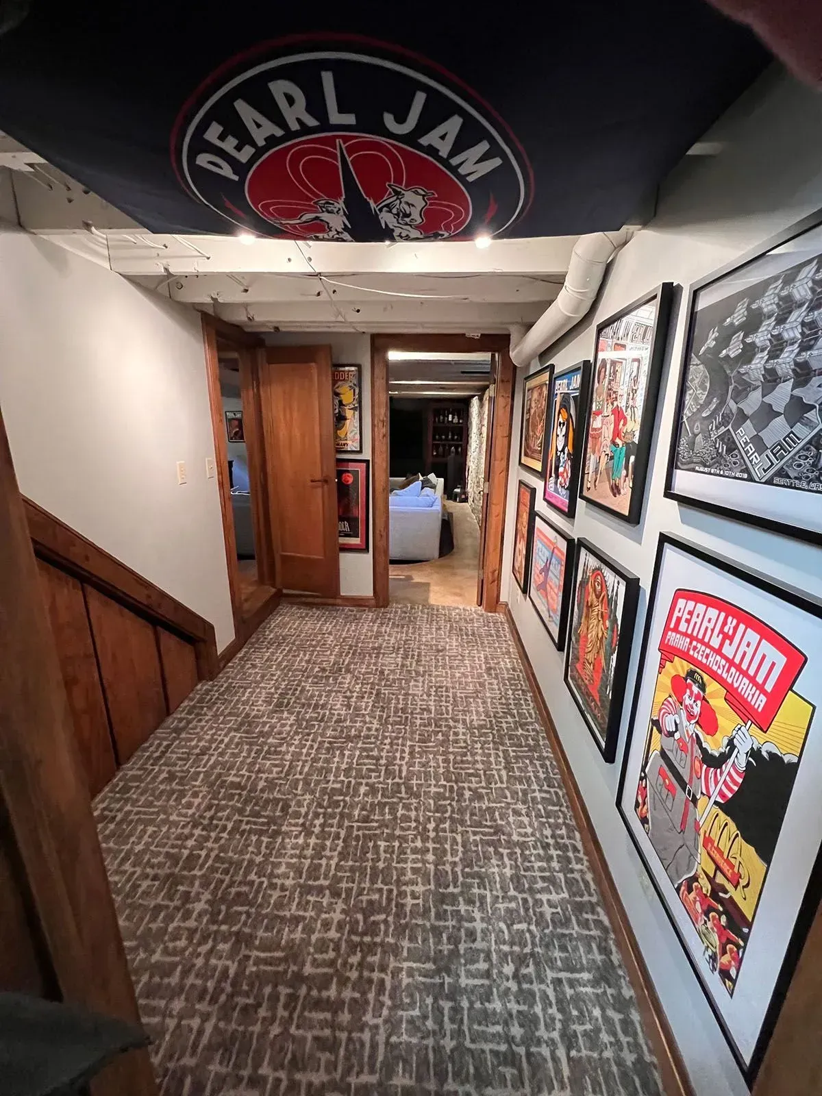 Hallway with Pearl Jam flag, concert posters, wooden stairs, and carpet.