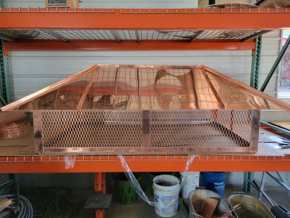 A copper chimney cap is sitting on top of a shelf in a warehouse.