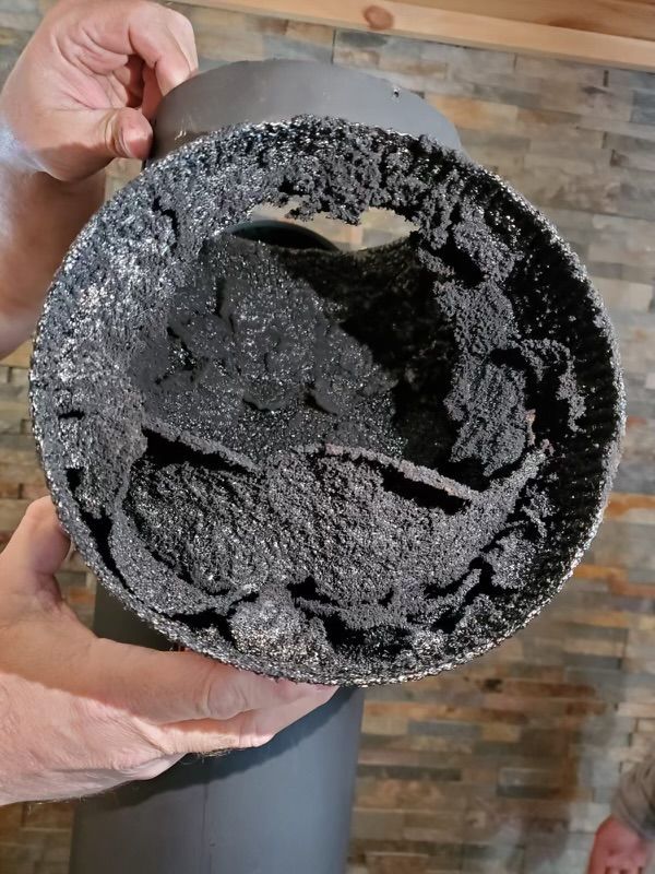 A person is holding a dirty chimney pipe in their hands.