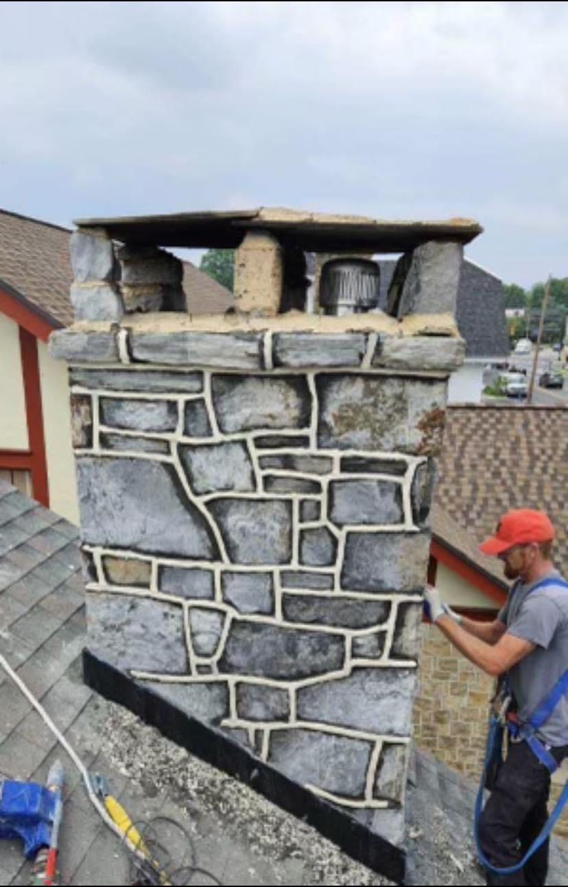 A man is working on a stone chimney on top of a roof.