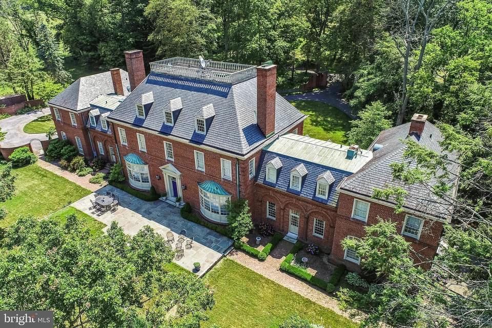 An aerial view of a large brick house surrounded by trees.