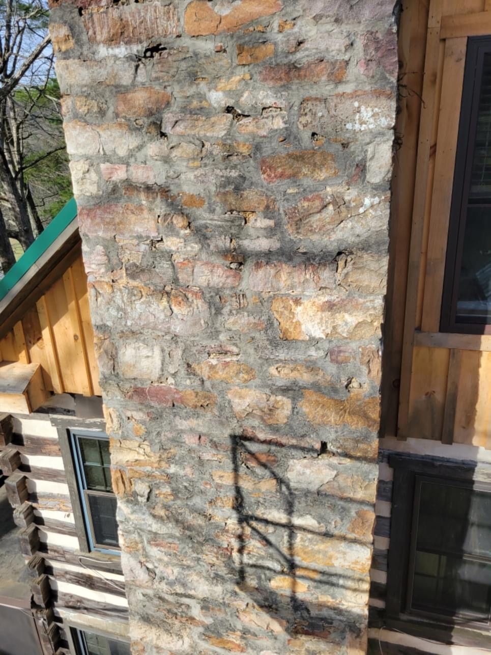 A large stone chimney on the side of a house.
