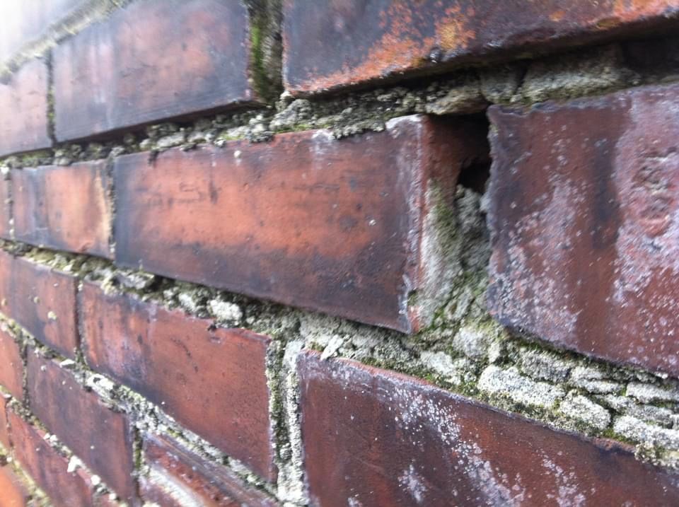 A close up of a brick wall with a hole in it.