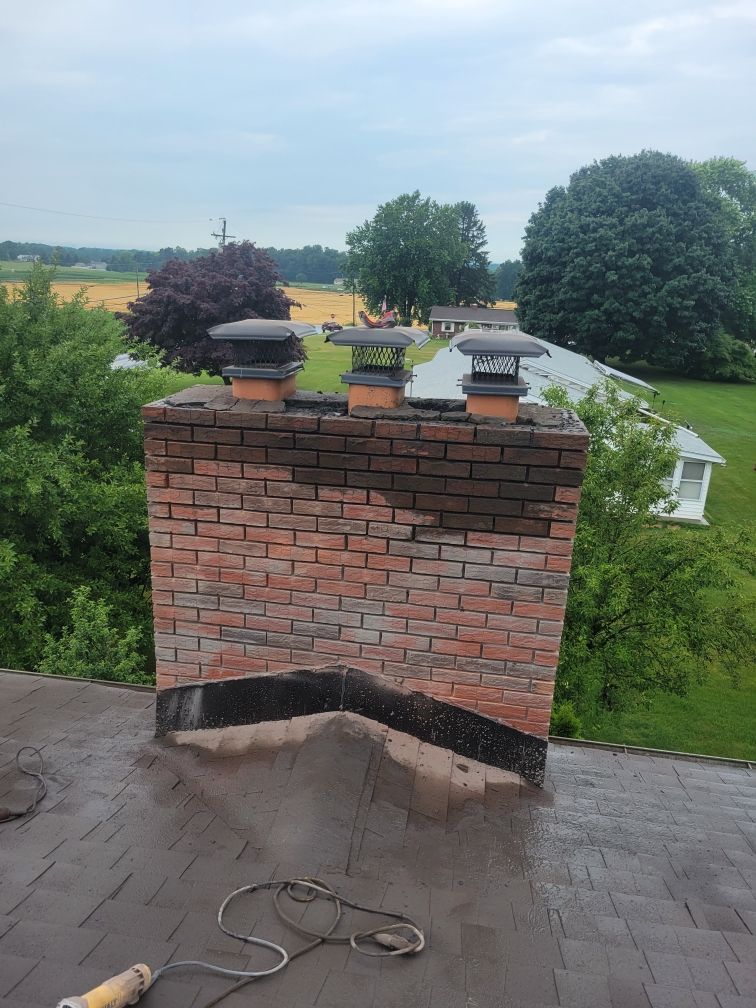 A brick chimney is sitting on top of a roof.
