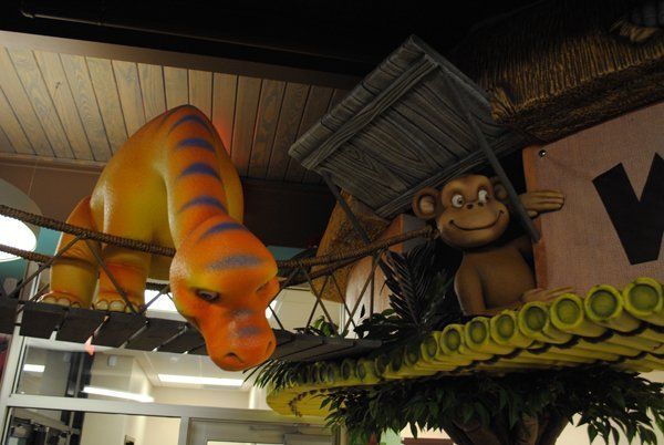 Orange dinosaur and smiling monkey figures on a jungle-themed playground.