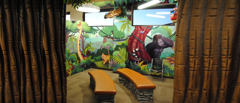 A jungle-themed waiting room with two benches, mural, and curtains.