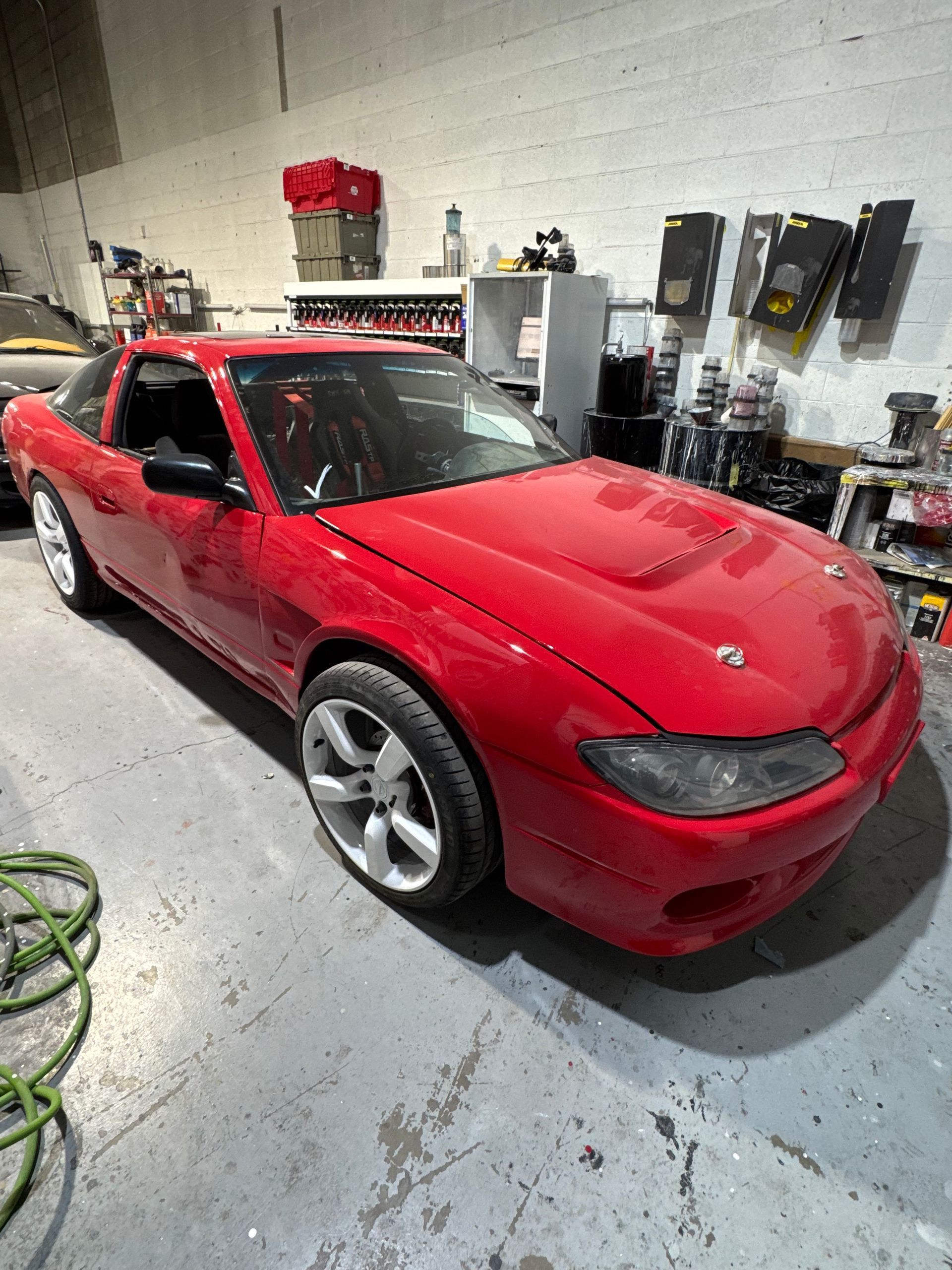Red sports car in a garage with tools and equipment on the walls