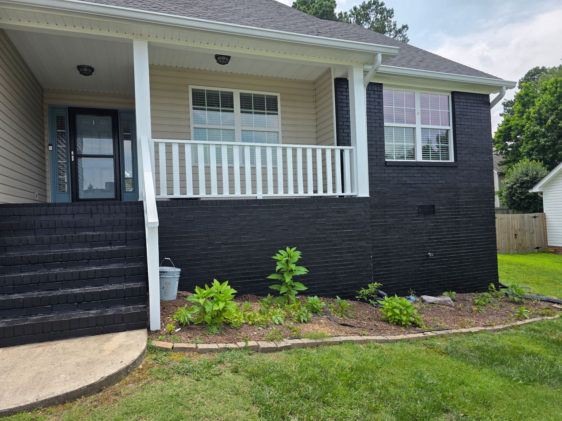 Black-painted brick house with white porch, steps, and trim