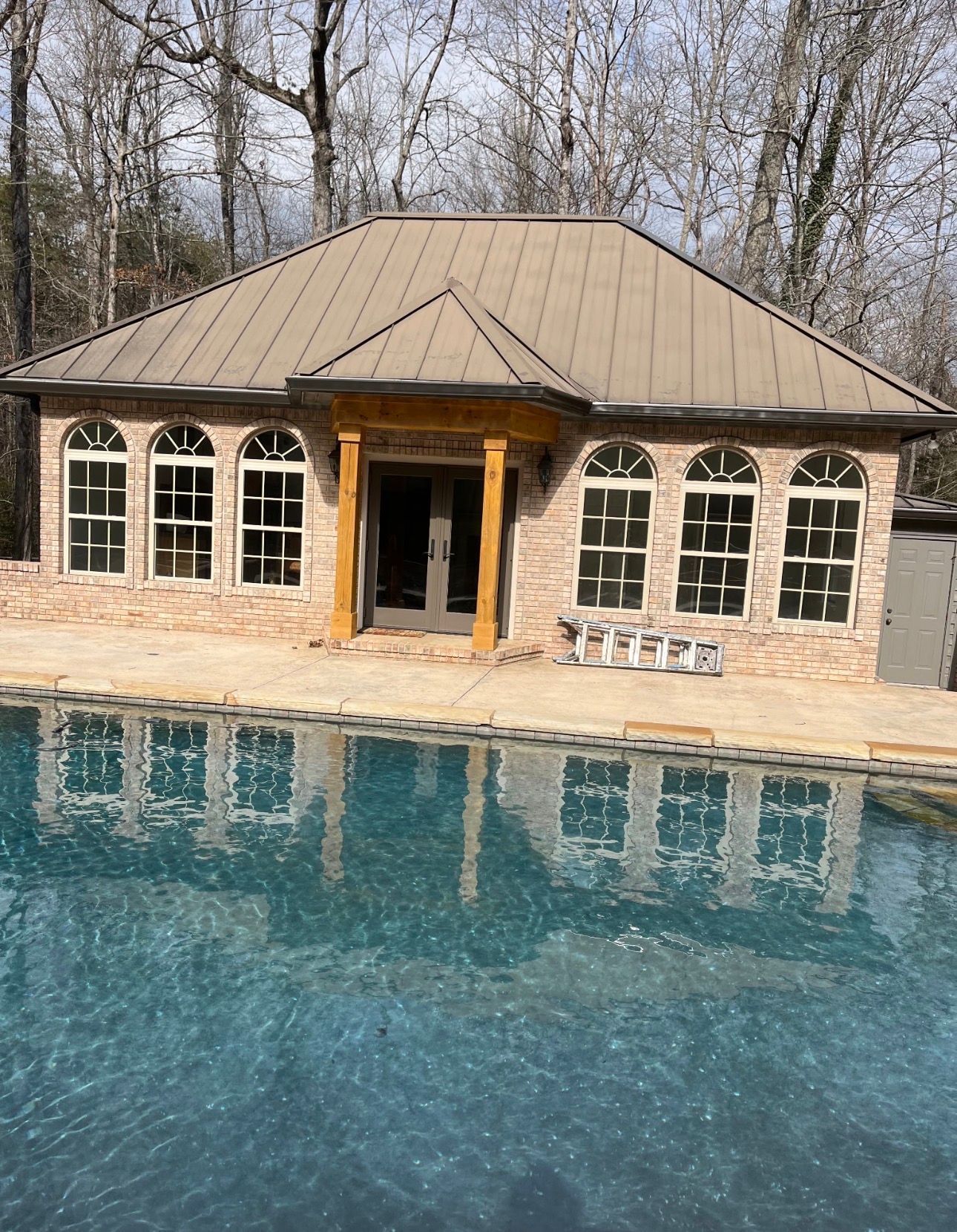 Poolside stone building with arched windows reflected in the pool.