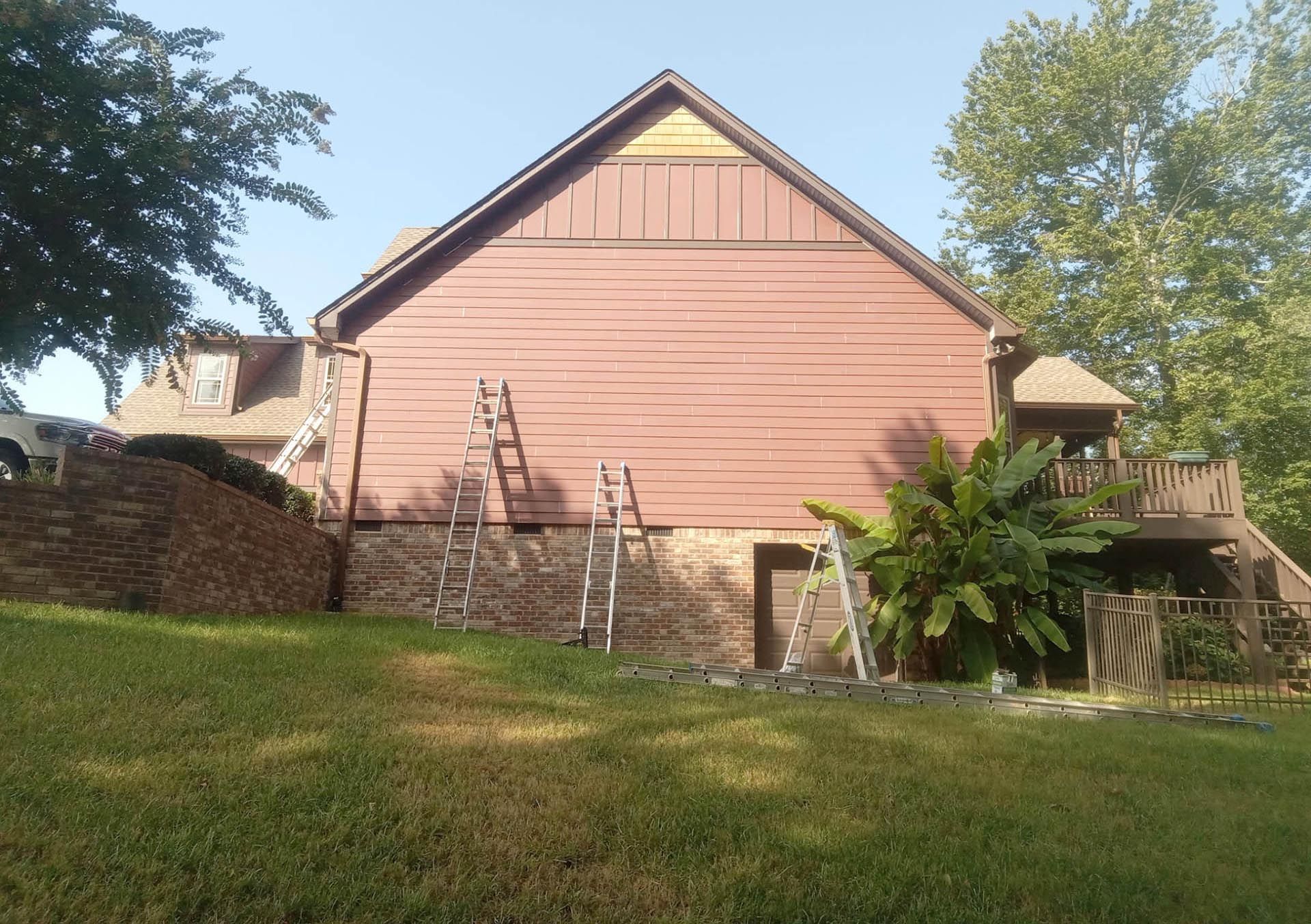 A rear view of a house with ladders leaning against the siding