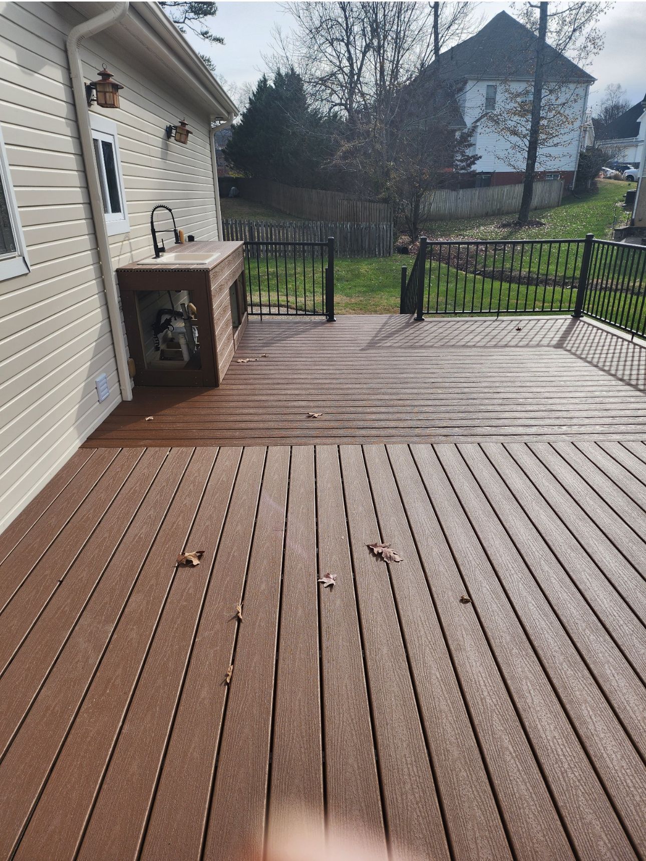 A wooden deck with a sink and stairs leading to a house
