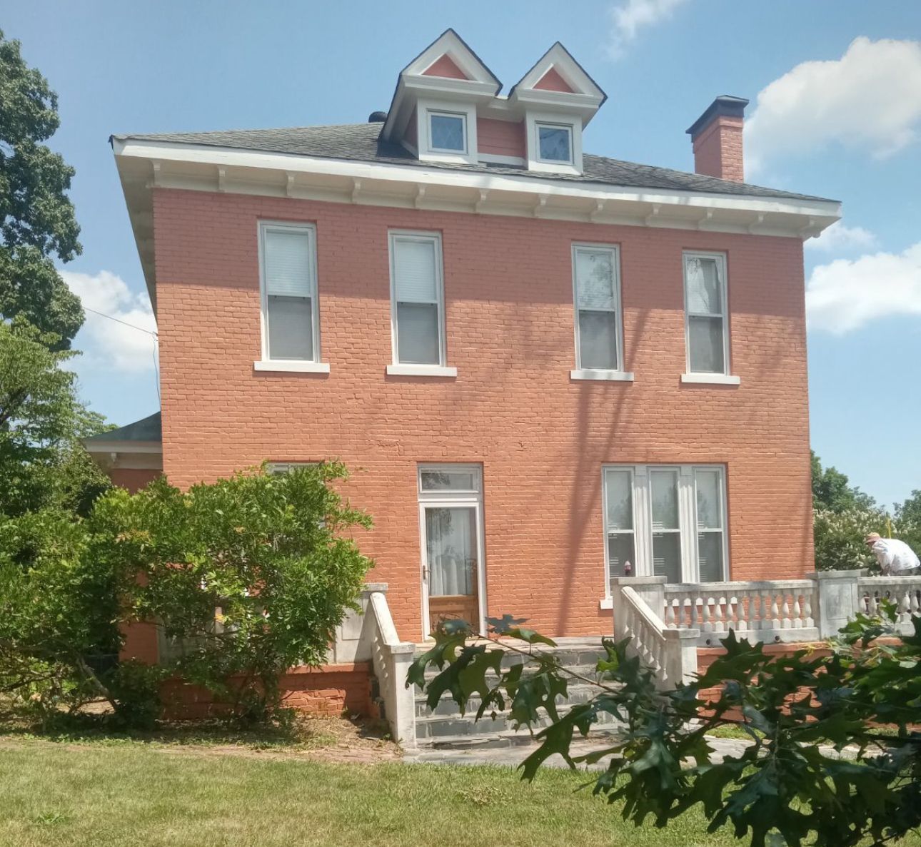 A large red brick house with a balcony and stairs