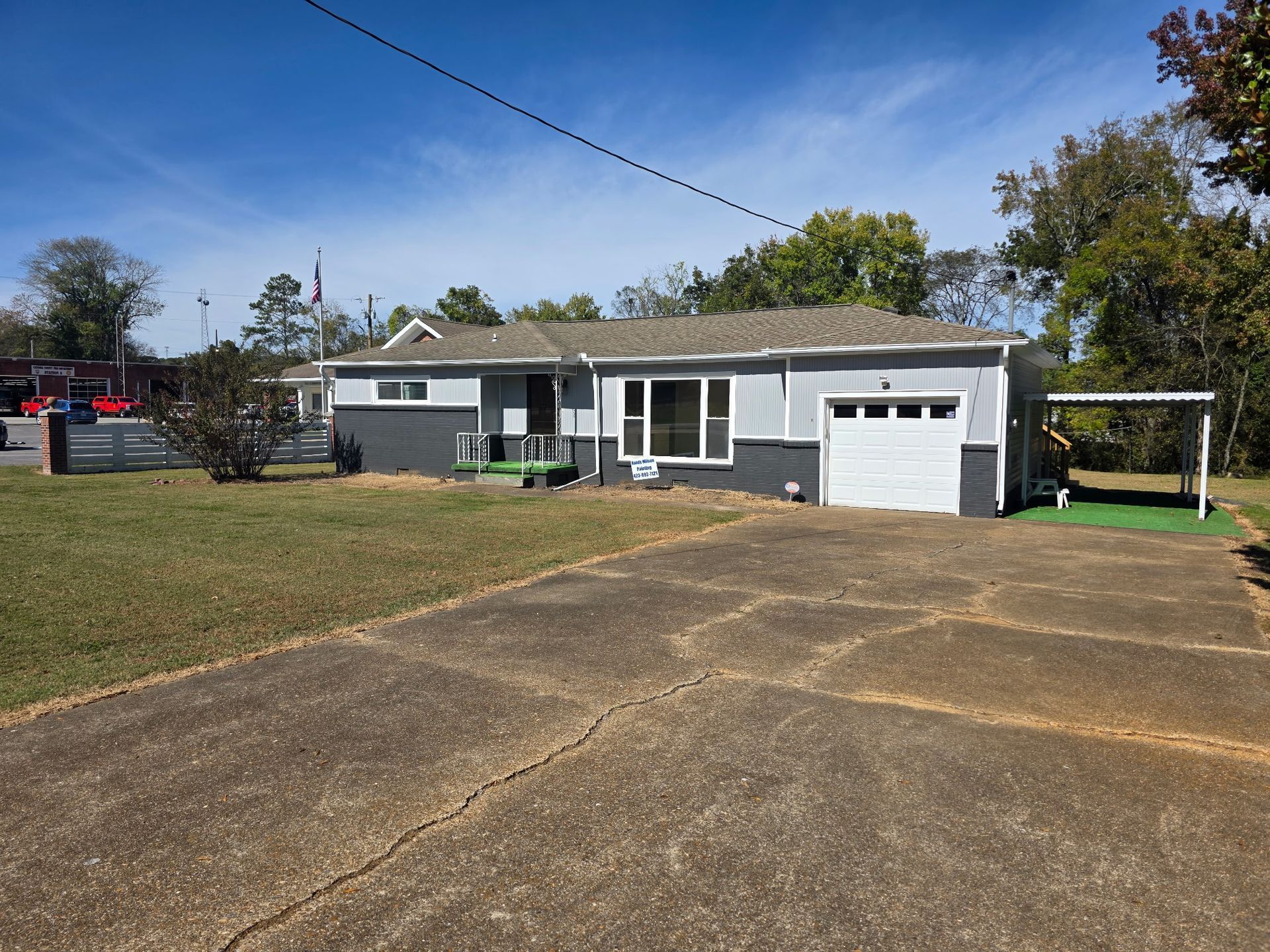 Gray and white house with a driveway and attached garage under a blue sky.