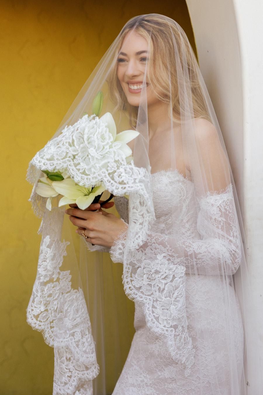The bride is wearing a veil and holding a bouquet of flowers.