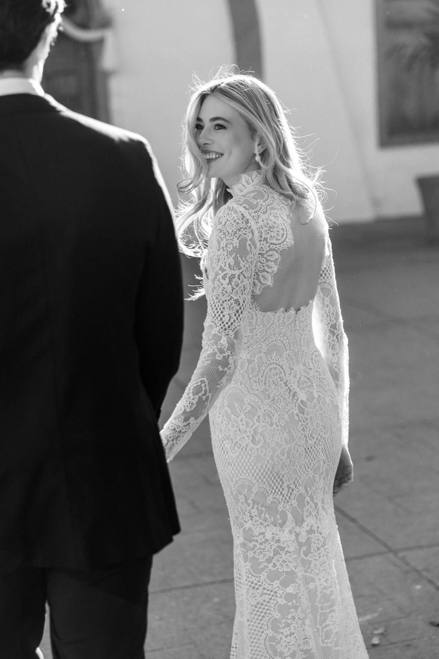 A black and white photo of a bride and groom holding hands.