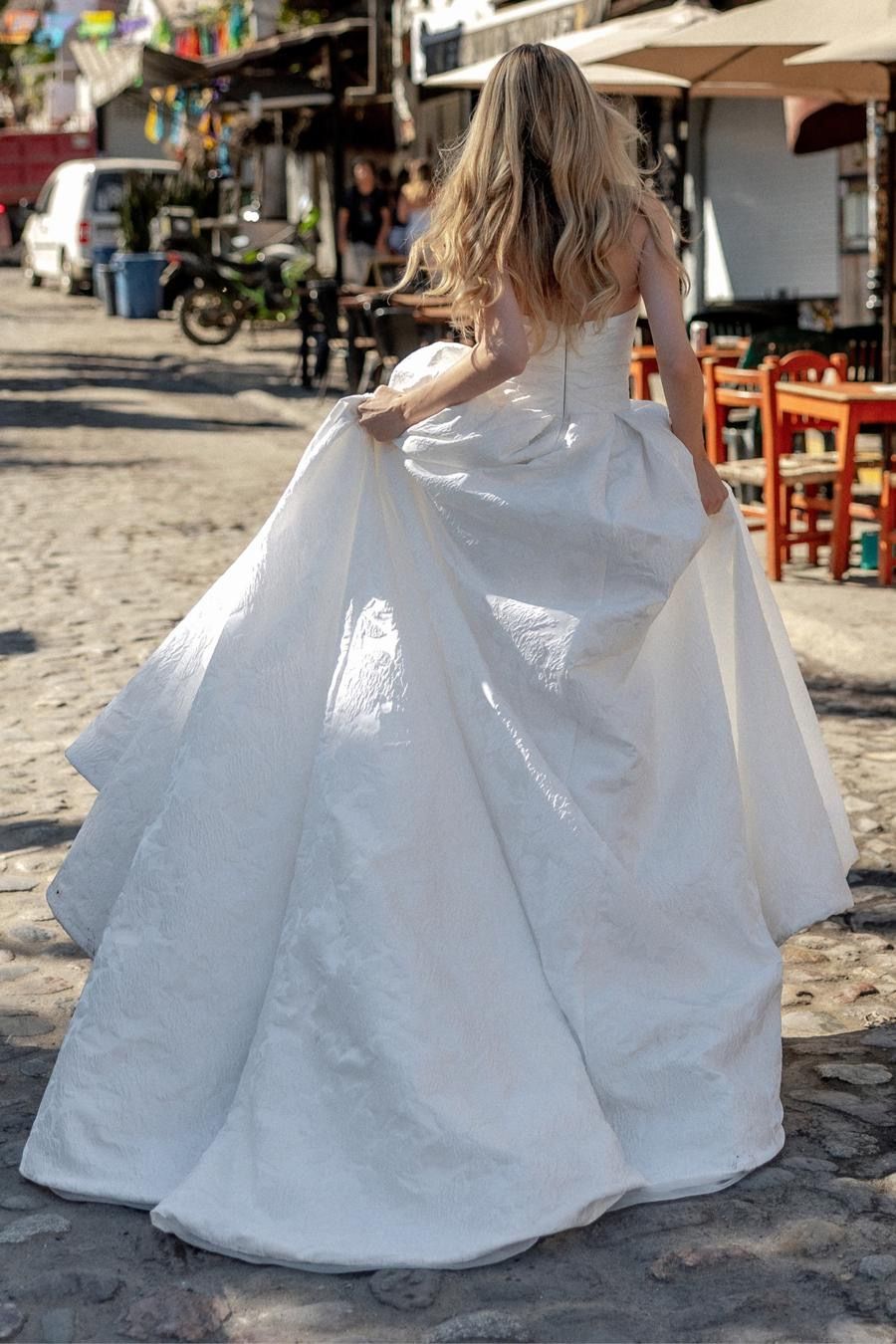 The back of a woman in a wedding dress is shown.
