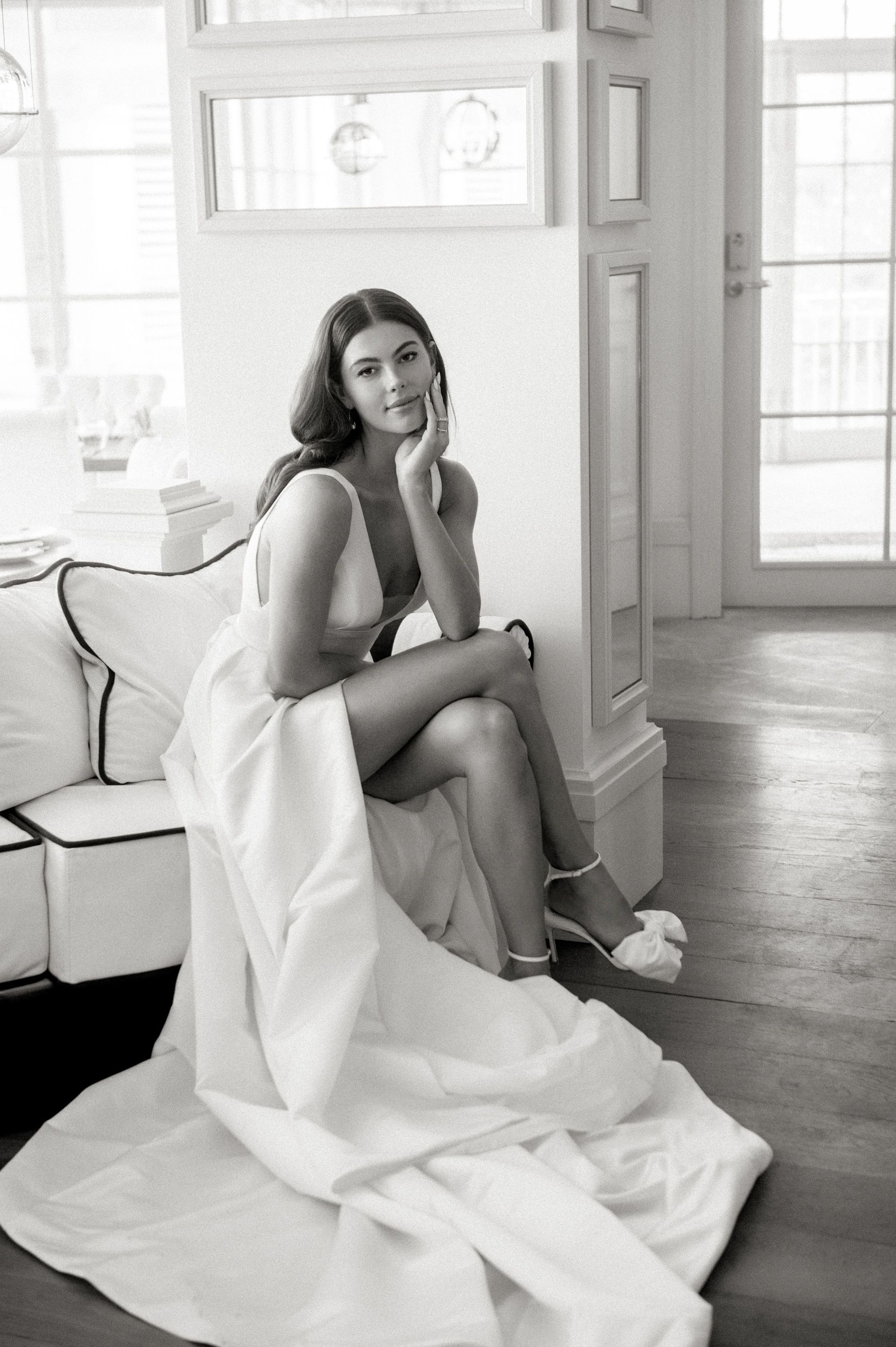 A woman in a wedding dress is sitting on a couch.