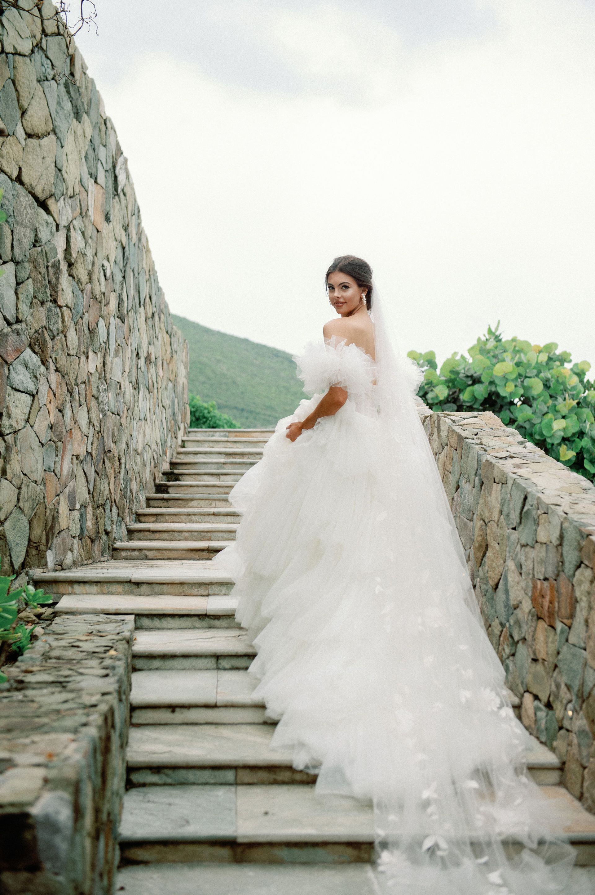A bride in a wedding dress is walking down a set of stairs.