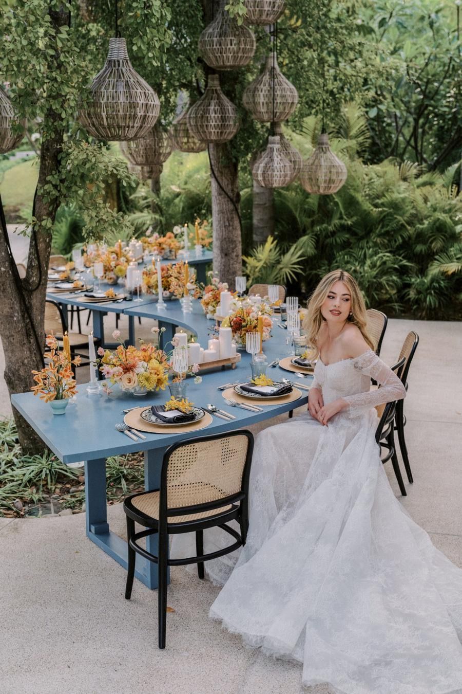 A woman in a wedding dress is sitting at a table with flowers on it.