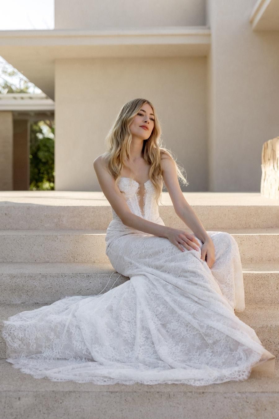 A woman in a wedding dress is sitting on a set of stairs.