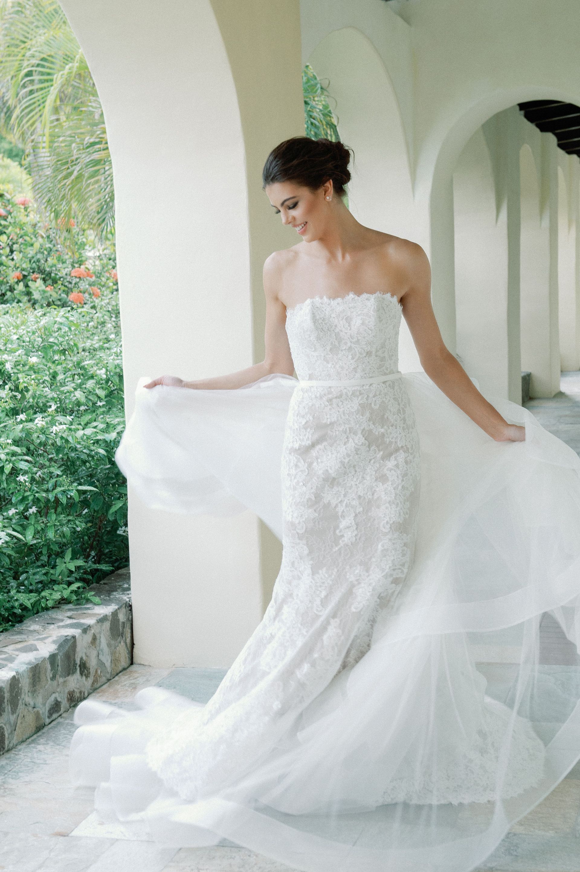 A woman in a white wedding dress is standing under an archway.