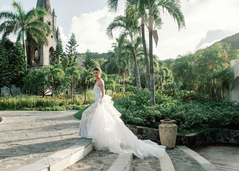 A bride in a wedding dress is standing on steps in front of a church.