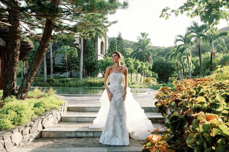A woman in a wedding dress is standing on stairs in a park.