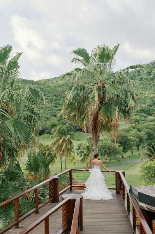 A bride in a wedding dress is standing on a wooden deck overlooking a golf course.